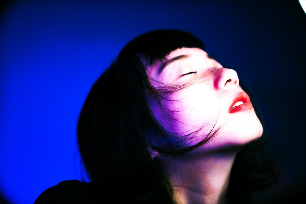 A face with eyes closed in blue and magenta light