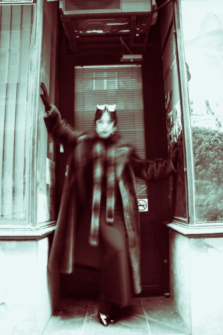 A figure in a checked coat in a doorway, washed in red