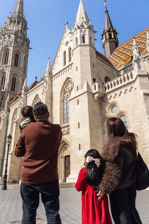 A family seen from behind, looking up at Matthias Church