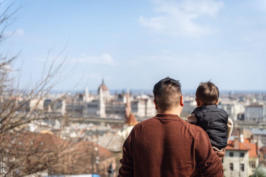A father holding his son, looking out over the Parliament and the Danube