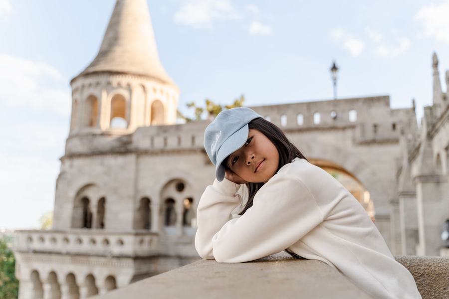A girl in a blue cap resting her head on a wall at Fisherman's Bastion