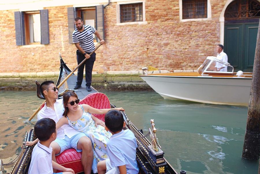 A mother and her three sons on a gondola in a Venetian canal