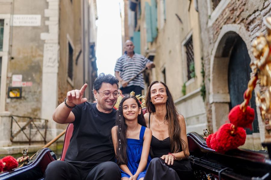 A family on a gondola in a narrow canal, the father pointing up