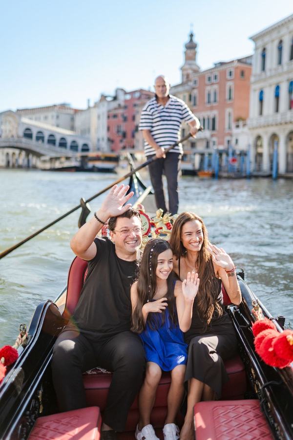 A family waving from a gondola on the Grand Canal near the Rialto Bridge