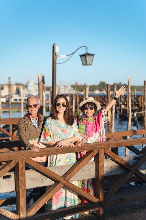 A family waving from a wooden pier on the Venetian lagoon
