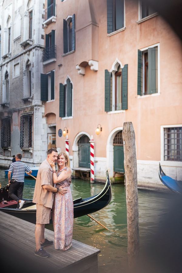 A couple embracing on a wooden pier beside a gondola