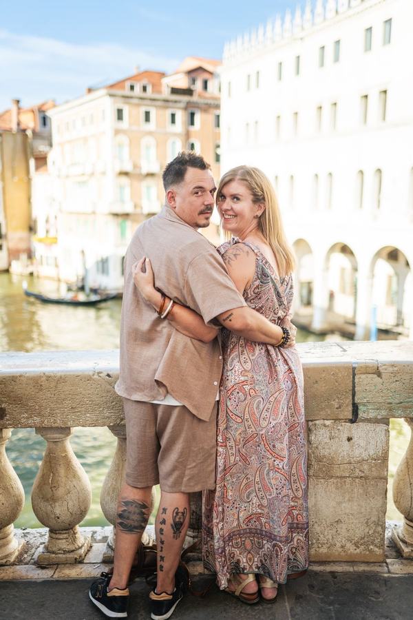 A couple seen from behind, looking back over their shoulders above the Grand Canal