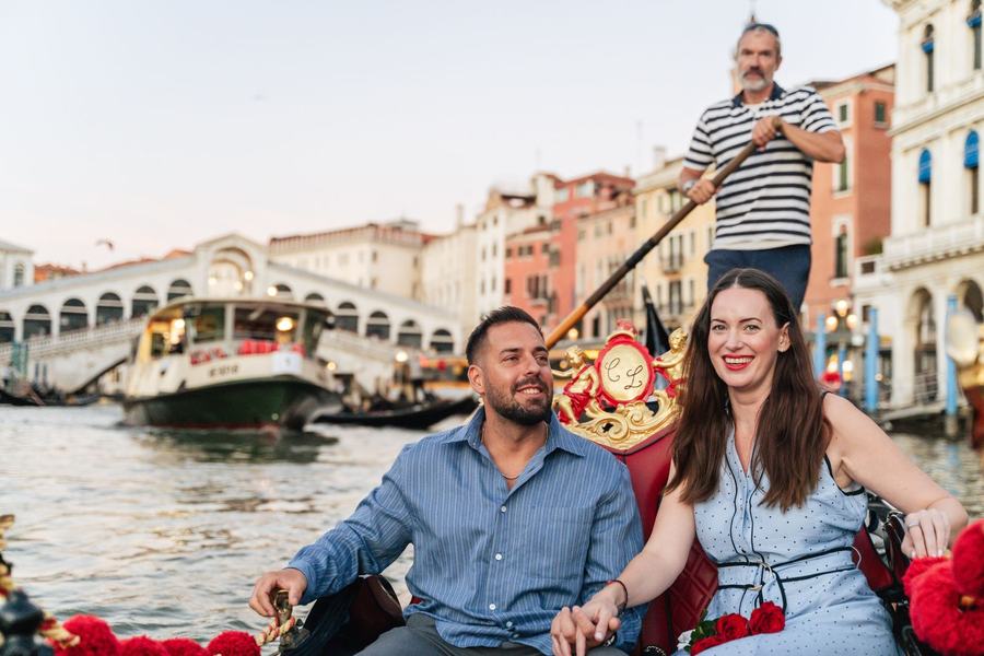 A smiling couple on a gondola on the Grand Canal near the Rialto Bridge