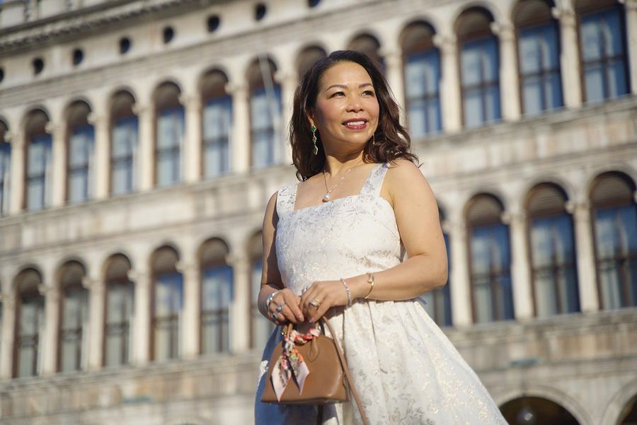 A woman in a white dress smiling in St Mark's Square